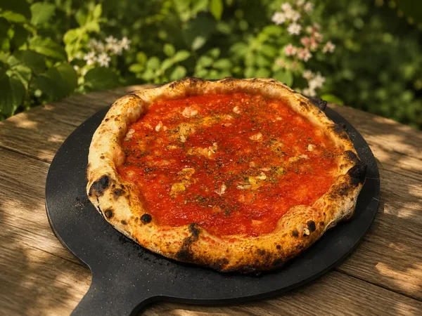 A marinara pizza on a peel, tomato with garlic and oregano and no cheese
