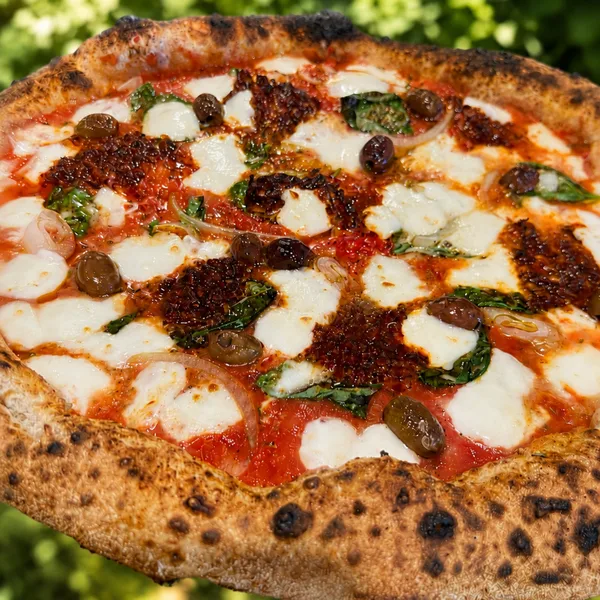 An nduja pizza, the nduja melted dark red across mozzarella with olives, red onion and basil