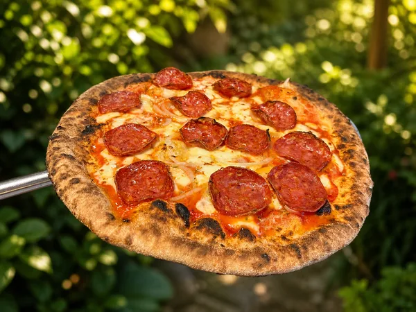 A pepperoni pizza fresh from the oven, the pepperoni cupped and crisped at the edges